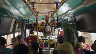 Alfonso Mendoza (Alca) saat menghibur penumpang di dalam bus, Barranquilla, Kolombia, Jumat (28/9). [AFP/ARBOLDA]