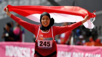 Sprinter Indonesia Karisma Evi Tiarani mengibarkan bendera merah putih usai finis terdepan dalam nomor 100 meter putri T42 dan T63 Asian Para Games 2018 di Stadion Utama Gelora Bung Karno, Jakarta, Rabu (10/10). [ANTARA FOTO/Akbar Nugroho Gumay]