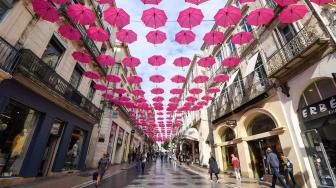 Pejalan kaki melintasi ratusan payung pink yang digantung di Montpellir, Prancis, Selasa (9/10). [AFP/PASCAL GUYOT]

