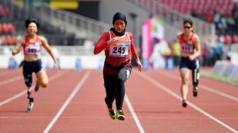 Sprinter Indonesia Karisma Evi Tiarani (tengah) memacu kecepatan saat berlaga dalam nomor 100 meter putri T42 dan T63 Asian Para Games 2018 di Stadion Utama Gelora Bung Karno, Jakarta, Rabu (10/10). [ANTARA FOTO/Akbar Nugroho Gumay]