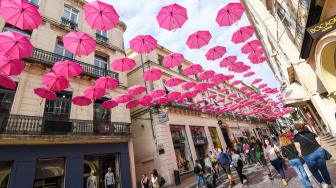 Pejalan kaki melintasi ratusan payung pink yang digantung di Montpellir, Prancis, Selasa (9/10). [AFP/PASCAL GUYOT]
