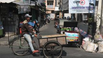 Penarik becak melintas  di kawasan Teluk Gong, Pejagalan Jakarta Utara, Kamis (11/10). (Suara.com/Fakhri Hermansyah)
