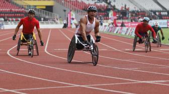 Pebalap kursi roda Indonesia Jaenal Aripin memacu kecepatanya saat berlaga di cabang atletik nomor balap kursi roda 200 meter T 54 di Stadion Utama Gelora Bung Karno, Jakarta, Jumat (12/10). [Suara.com/Muhaimin A Untung]