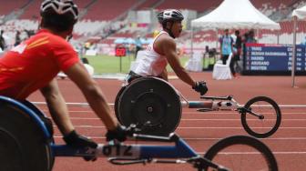 Pebalap kursi roda Indonesia Jaenal Aripin memacu kecepatanya saat berlaga di cabang atletik nomor balap kursi roda 200 meter T 54 di Stadion Utama Gelora Bung Karno,  , Jakarta, Jumat (12/10). [Suara.com/Muhaimin A Untung]