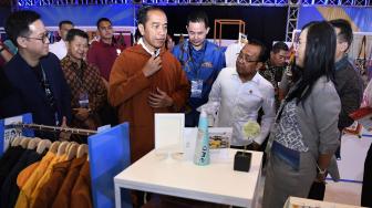 
Presiden Joko Widodo (tengah) didampingi Mensesneg Pratikno (kedua kanan) dan Co Founder Ideafest Bernhard Subiakto (kiri) membeli jaket dalam pameran Ideafest 2018 di JCC, Senayan, Jakarta, Jumat (26/10). [ANTARA FOTO/Puspa Perwitasari]