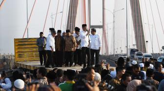 Presiden Joko Widodo (kedua kanan) didampingi Menteri PUPR Basuki Hadimuljono (kedua kiri) dan Sekretaris Kabinet Pramono Anung (kanan) serta pejabat setempat dan para ulama berada diatas truk saat meresmikan pembebasan tarif tol Jembatan Suramadu di Surabaya, Jawa Timur, Sabtu (27/10/).  [ANTARA FOTO/Zabur Karuru]