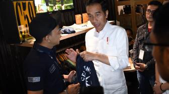 Calon Presiden Nomor Urut 01 Joko Widodo memamerkan kaos  sebelum berdiskusi dengan masyarakat kreatif Bandung di Simpul Space, Bandung, Jawa Barat, Sabtu (10/11). [ANTARA FOTO/Wahyu Putro]
