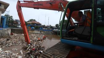 Petugas kebersihan DKI Jakarta mengeruk sampah menggunakan alat berat di pintu air Manggarai, Jakarta Selatan, Senin (12/11). [Suara.com/Muhaimin A Untung] 