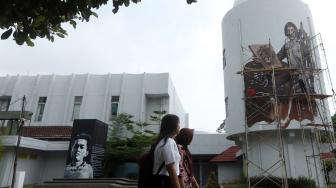 Seorang melintas di depan mural tokoh Chairil Anwar dan raden Saleh  di Gedung Taman Ismail Marzuki, Jakarta, Senin (12/10). [Suara.com/Muhaimin A Untung] 