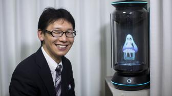 Akihiko Kondo berpose di sebelah hologram yang menampilkan gambar aktris virtual, Hatsune Miku di Tokyo, Jepang, Sabtu (10/11). (AFP/Behrouz MEHRI)