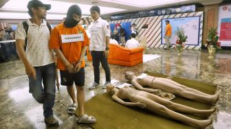 Tersangka HS melakukan reka ulang kejadian saat Prarekonstruksi kasus pembunuhan satu keluarga Diperum Nainggolan alias Gaban di Polda Metro Jaya, Jakarta, Senin (19/11). [Suara.com/Muhaimin A Untung]