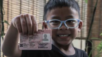 Seorang anak memperlihatkan Kartu Identitas Anak (KIA) di Pondok Kelapa, Jakarta Timur, Selasa (20/11).(Suara.com/Fakhri Hermansyah)