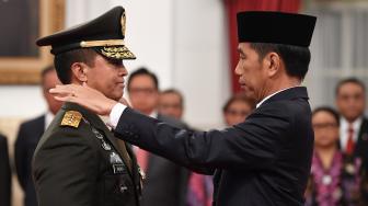 Presiden Joko Widodo (kanan) memasangkan tanda pangkat jabatan kepundak Kepala Staf Angkatan Darat (KSAD) yang baru Jenderal TNI Andika Perkasa (kiri) seusai pelantikan di Istana Merdeka, Jakarta, Kamis (22/11). [ANTARA FOTO/Wahyu Putro ]