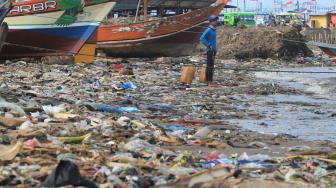 Nelayan menyandarkan perahunya di bibir pantai yang dipenuhi sampah plastik di Desa Dadap, Indramayu, Jawa Barat, Senin (26/11). ANTARA FOTO/Dedhez Anggara