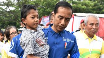 Presiden Joko Widodo (kiri) menggendong siswa penyandang disabilitas asal Sukabumi Mukhlis Abdul Holik disela Peringatan Hari Disabilitas Internasional Tahun 2018 di Bekasi, Jawa Barat, Senin (3/12). [ANTARA FOTO/Puspa Perwitasari]