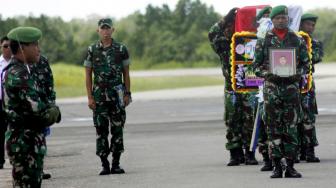 Prajurit TNI AD membawa karangan bunga dan peti jenazah Sertu Anumerta Handoko di pelataran Bandara DEO Kota Sorong, Papua Barat, Kamis (6/12). [ANTARA FOTO]