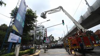 Seorang pria memanjat baliho di kawasan Kampus Universitas Al Azhar Jalan Sisingamangaraja, kebayoran Baru, Jakarta Selatan, Kamis (6/12). [Suara.com/Muhaimin A Untung]