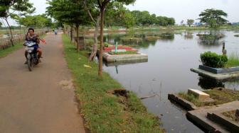 Warga beraktifitas di pemakaman yang terendam banjir di daerah Semper, Jakarta Utara, Sabtu (8/12). (Suara.com/Fakhri Hermansyah)