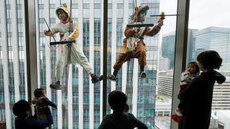 Petugas pembersih jendela berpakaian seperti anjing dan babi hutan membersihkan jendela-jendela hotel Ryumeikan, di Tokyo, Jepang, Kamis (13/12). [Kazuhiro NOGI / AFP]