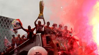 Pendukung Persija Jakarta The Jak mania menyambut iring-iringan pemain beserta  official di Thamrin, Jakarta Pusat, Sabtu (15/12).  [Suara.com/Fakhri Hermansyah]