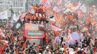 Pendukung Persija Jakarta The Jak mania menyambut iring-iringan pemain beserta  official di Thamrin, Jakarta Pusat, Sabtu (15/12).  [Suara.com/Fakhri Hermansyah]