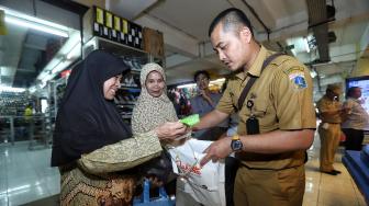 Petugas Dinas Lingkungan Hidup DKI Jakarta dan Perumda Pasar Jaya melakukan kegiatan operasi tukar kresek ke pembeli di Pasar Jaya Kramat Jati, Selasa (18/12). [Suara.com/Muhaimin A Untung]