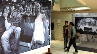 Pengunjung melintas dekat karya dalam acara Pameran Foto "Tanpa Batas" karya Tjandra Moh Amin di Galeri Cipta III, Taman Ismail Marzuki, Jakarta, Selasa (18/12). [Suara.com/Fakhri Hermansyah]