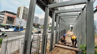 Pekerja melakukan pengerjaan proyek revitalisasi Jembatan Penyeberangan Orang (JPO) Bundaran Senayan di Jakarta, Selasa (18/12). [Suara.com/Muhaimin A Untung]