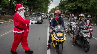 Warga berkostum Sinterklas membagikan hadiah kepada pengguna jalan di Solo, Jawa Tengah, Jumat (21/12). ANTARA FOTO/Mohammad Ayudha