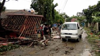 Warga memeriksa kerusakan rumah mereka di pantai Carita, Anyer, Banten, Minggu (23/12). [Semi / AFP]