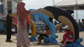 Pengunjung bermain di Pantai Langon, Ancol, Jakarta, Senin (25/12). [Suara.com/Muhaimin A Untung]