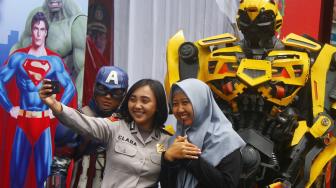 Polwan melakukan swafoto bersama relawan berkostum superhero Kapten Amerika dan Bumblebee di Gereja Katedral Ijen, Malang, Jawa Timur, Selasa (25/12/2018). [ANTARA FOTO/Ari Bowo Sucipto]