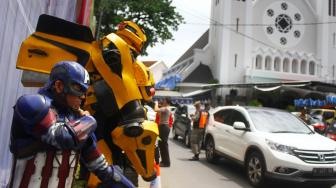 Relawan yang mengenakan kostum karakter superhero Kapten Amerika dan Bumblebee berjaga di depan Gereja Katedral Ijen, Malang, Jawa Timur, Selasa (25/12/2018). [ANTARA FOTO/Ari Bowo Sucipto]