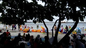 Pengunjung bermain di Pantai Langon, Ancol, Jakarta, Senin (25/12). [Suara.com/Muhaimin A Untung]