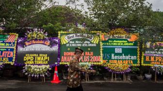 Pelayat melintas di depan karangan bunga saat melayat ke rumah duka Paman Presiden Joko Widodo almarhum Mulyono Herlambang di Gayam, Sukoharjo, Jawa Tengah, Jumat (4/1).  [ANTARA FOTO/Mohammad Ayudha]
