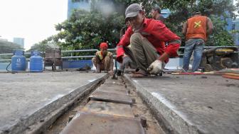 Petugas melakukan perbaikan Jembatan layangnyang renggang di Jalan Layang, Jalan Industri Raya, Kemayoran, Jakarta Pusat, Minggu (6/1). [Suara.com/Muhaimin A Untung] 