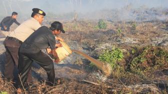 Personil Kepolisian Polres Aceh Barat bersama warga memadamkan api yang membakar lahan gambut dengan cara manual di Kawasan Desa Seuneubok, Kecamatan Johan Pahlawan, Aceh Barat, Aceh, Minggu (6/1). ANTARA FOTO/Syifa Yulinnas