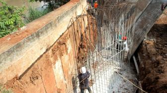 Perbaikan tanggul sungai dan jalan yang amblas di perumahan Kawasan Kemang Pratama, Bekasi, Jawa Barat, Selasa (8/1). [Suara.com/Fakhri Hermansyah]