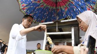 Presiden Joko Widodo membeli jajanan Cilok saat meninjau Program Mekaar binaan PNM di Lapangan Sepak Bola Gongseng, Jakarta Timur, Kamis (10/1).  [ANTARA FOTO/Puspa Perwitasari]