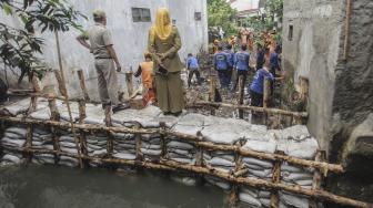 Petugas PPSU membersihkan lumpur yang menggenangi jalan pemukiman warga karena tanggul aliran Kali Pulo jebol di Kelurahan Jati Padang, Kecamatan Pasar Minggu, Jakarta, Senin (14/1). [ANTARA FOTO/Muhammad Adimaja]