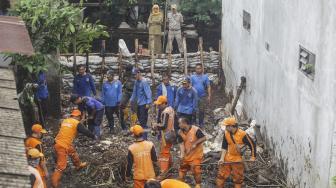 Petugas PPSU membersihkan lumpur yang menggenangi jalan pemukiman warga karena tanggul aliran Kali Pulo jebol di Kelurahan Jati Padang, Kecamatan Pasar Minggu, Jakarta, Senin (14/1). [ANTARA FOTO/Muhammad Adimaja]