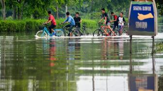 Seorang anak melintas di Jalan Raya yang terendam banjir di Porong, Sidoarjo, Jawa Timur, Sabtu (19/1/). [ANTARA FOTO/Umarul Faruq]