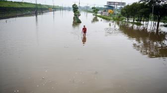 Warga melintas di Jalan Raya yang terendam banjir di Porong, Sidoarjo, Jawa Timur, Sabtu (19/1). [ANTARA FOTO/Umarul Faruq]