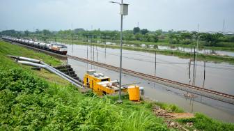 Kereta api melaju di samping Jalan Raya Porong yang terendam banjir di Porong, Sidoarjo, Jawa Timur, Sabtu (19/1/). [ANTARA FOTO/Umarul Faruq]