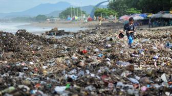 Seorang anak berjalan di atas tumpukan sampah plastik yang berserakan di Pantai Padang, Sumatera Barat, Selasa (22/1). [ANTARA FOTO/Iggoy el Fitra]