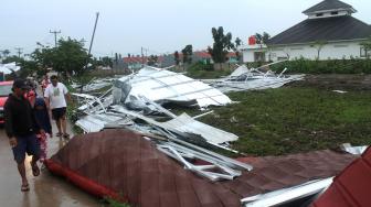 Warga melintas di dekat rumah yang rusak akibat diterjang angin puting beliung di kawasan Jejalen, Bekasi, Jawa Barat, Selasa (22/1). [ANTARA FOTO/Risky Andrianto]