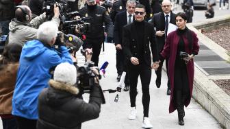 Pemain Juventus Cristiano Ronaldo bersama kekasihnya Georgina Rodriguez saat menghadiri sidang dugaan penggelapan pajak di Kota Madrid, Spanyol, Selasa (22/1). [PIERRE-PHILIPPE MARCOU / AFP]