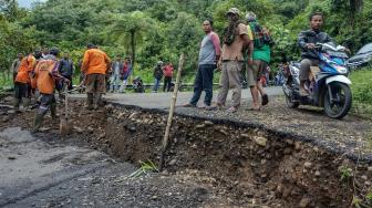 Sejumlah pekerja memperbaiki jalan yang ambles di Desa Tenogo, Paninggaran, Kabupaten Pekalongan, Jawa Tengah, Rabu (23/1). [ANTARA FOTO/Harviyan Perdana Putra]