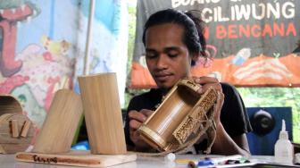 Anggota Komunitas Ciliwung Depok (KCD)  saat membuat kerajinan tangan dengan menggunakan bambu bekas di sekitar kawasan bantaran Sungai Ciliwung, Depok Jawa Barat, Jum'at (25/1). [Suara.com/Fakhri Hermansyah]