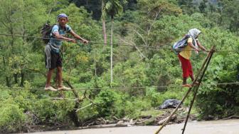 Warga menyeberangi sungai Krueng Meureubo dengan menggunakan jembatan tali yang terbuat dari kabel listrik menuju Desa Sikundo, Kecamatan Pante Ceureumen, Aceh Barat, Aceh, Sabtu (2/1). ANTARA FOTO/Syifa Yulinnas